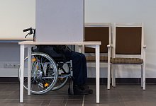 Rentner im Rollstuhl während der Stimmabgabe in einer Wahlkabine - Robert Michael/dpa-Zentralbild/dpa-tmn