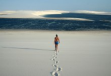 Frau läuft durch Dünenlandschaft zu einer kleinen Lagune - Manuel Meyer/dpa-tmn