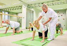 Physiotherapeutin gibt Hilfestellung bei Rückengymnastik - picture alliance / Zoonar