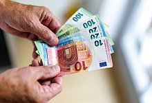 Ein &auml;lterer Mann h&auml;lt Euro Banknoten in der Hand - Matthias Balk/dpa