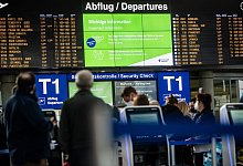Urlauber stehen vor einer Anzeigetafel am Flughafen - Christoph Schmidt/dpa/dpa-tmn