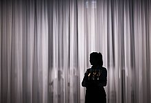 Eine Servicemitarbeiterin steht vor einem hellen Vorhang - Sebastian Gollnow/dpa/dpa-tmn