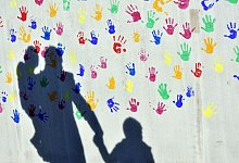 Schatten auf einer Wand mit bunten Handabdr&uuml;cken - Peter Kneffel/dpa/dpa-tmn