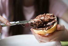 Ein Br&ouml;tchen wird mit Nuss-Nougat-Creme beschmiert - Silvia Marks/dpa-tmn