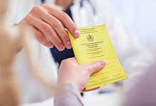 Ein Arzt nimmt den Impfausweis seiner Patientin entgegen - Christin Klose/dpa-tmn