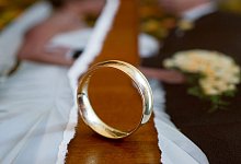 EIn Ehering liegt neben einem zerrissenem Hochzeitsfoto - Patrick Pleul/dpa/dpa-tmn