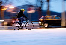 Ein Fahradfahrer auf einer verschneiten Straße im Winter - Julian Stratenschulte/dpa/dpa-tmn