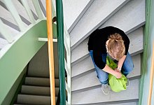 Eine Frau sitzt in einem Treppenhaus auf einer Treppenstufe - Peter Steffen/dpa/dpa-tmn