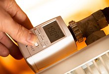 Eine Frau stellt ein digitales Thermostat ein - Franziska Gabbert/dpa-tmn