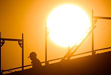 Bauarbeiter auf Ger&uuml;st im Sonnenlicht - Julian Stratenschulte/dpa/dpa-tmn