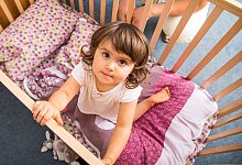 M&auml;dchen schaut aus ihrem Kinderbett - Christin Klose/dpa-tmn