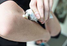 Person cremt Ellbogen mit einer Salbe ein - Franziska Gabbert/dpa-tmn