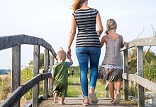 Eine Mutter läuft mit ihren Kindern über einen Steg - Benjamin Nolte/dpa-tmn