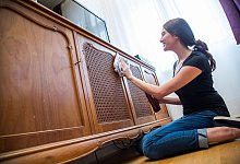 Eine Frau poliert eine antike Kommode - Christin Klose/dpa-tmn