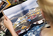 Eine Person betrachtet ein Fotobuch - Mascha Brichta/dpa-tmn