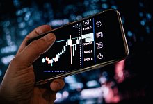 Mann schaut sich AKtienkurse auf dem Smartphone an - Zacharie Scheurer/dpa-tmn