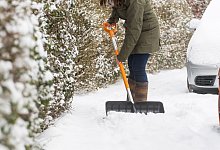 Eine Frau schippt Schnee auf dem Gehweg vor ihrem Haus - Benjamin Nolte/dpa-tmn