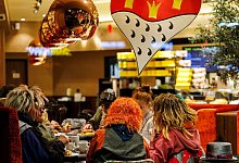 Karnevalisten sitzen vor dem Rosenmontagsumzug in einer Bäckerei - Christoph Reichwein/dpa