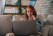 Frau schaut nachdenklich auf einen Laptop - Zacharie Scheurer/dpa-tmn