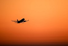 Ein Flugzeug hebt vor orangefarbenem Himmel ab - Jan Woitas/dpa/dpa-tmn