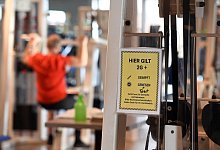 Ein Mann trainiert in einem Fitnessstudio, das bereits im Aushang die 2G+-Regelung hat. - picture alliance/dpa