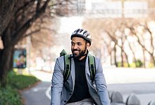 Portrait of man commuter riding bicycle in city, sustainable lifestyle. - AOK/hfr./Halfpoint Images