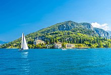 Italy, Veneto, Punta San Vigilio, Lake Garda in summer with mountain and single sailboat in background, MHF00749 - IMAGO/Westend61