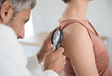 dermatologe blick auf frau maulwurf mit lupe - picture alliance / PantherMedia