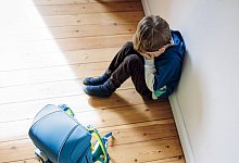 Symbolfoto zum Thema Angst vor der Schule. Ein Junge sitzt traurig in seinem Kinderzimmer neben seinem Schulranzen und v - IMAGO/photothek