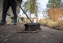 Person fegt eine Terrasse - Florian Schuh/dpa-tmn