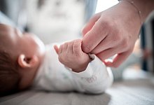 Ein Baby h&auml;lt sich an der Hand einer Erwachsenen fest - Foto: Fabian Strauch/dpa/Archivbild