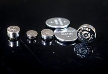 Verschiedene Knopfbatterien liegen auf einer Glasplatte - Christoph Schmidt/dpa/dpa-tmn