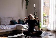 Eine Frau sitzt in ihrem Wohnzimmer auf dem Boden - Rafael Fernandez Torres/Westend61/dpa-tmn