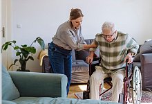 Frau k&uuml;mmert sich um einen &auml;lteren Mann im Rollstuhl - Halfpoint/Westend61/dpa-tmn