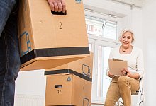 Eine Frau sitzt auf einem Hocker, ein Mann trägt Umzugskartons - Christin Klose/dpa-tmn/dpa