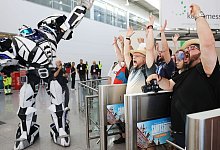 Computerspiel-Fans feiern gemeinsam mit einem Roboter den Einlass zur Messe. - Oliver Berg/dpa