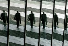 Spiegelung eines Mannes mit Aktentasche - picture alliance / Oliver Berg/dpa/dpa-tmn