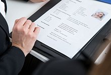 Eine Frau schaut sich eine Bewerbungsmappe an - Christin Klose/dpa-tmn