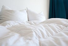 Bettdecken und Kissen liegen auf einem Bett - Foto: Andrea Warnecke/dpa-tmn