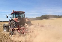 Verstaubt: Ein Traktor auf dem Stoppelfeld zieht eine braune Wolke hinter sich her. - Jobst L&uuml;deking