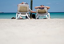Urlauber liegen am Strand auf Mallorca - Julian Stratenschulte/dpa/dpa-tmn