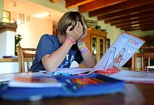 Junge hält sich bei den Hausaufgaben den Kopf - Julian Stratenschulte/dpa/dpa-tmn