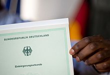 Eine Person hält eine Urkunde in der Hand - Julian Stratenschulte/dpa/dpa-tmn