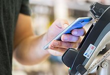 Mann h&auml;lt im Supermarkt ein Smartphone an das Kassenterminal - Franziska Gabbert/dpa-tmn