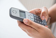 Frau hält ein Festnetztelefon in den Händen - Christin Klose/dpa-tmn