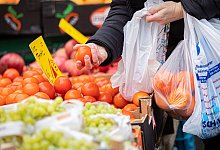 Eine Kundin begutachtet eine Tomate auf einem Wochenmarkt in Hannover. Wegen der steigenden Inflation müssen viele Menschen in Deutschland den Gürtel enger schnallen, - Moritz Frankenberg/dpa