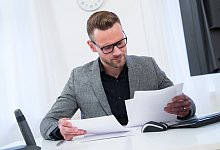 Ein Mann sieht im Büro in Unterlagen - Christin Klose/dpa-tmn