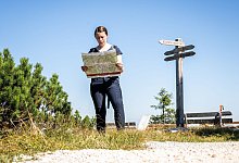 Wanderin schaut auf eine Wanderkarte - Benjamin Nolte/dpa-tmn