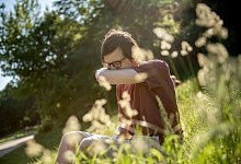 Mann in einem Park niest - Zacharie Scheurer/dpa-tmn