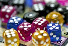 Bunte W&uuml;rfel liegen auf einem Tisch - Roland Weihrauch/dpa/dpa-tmn